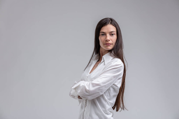 Portrait of long-haired brunette woman standing with arms crossed - Foto, Imagen