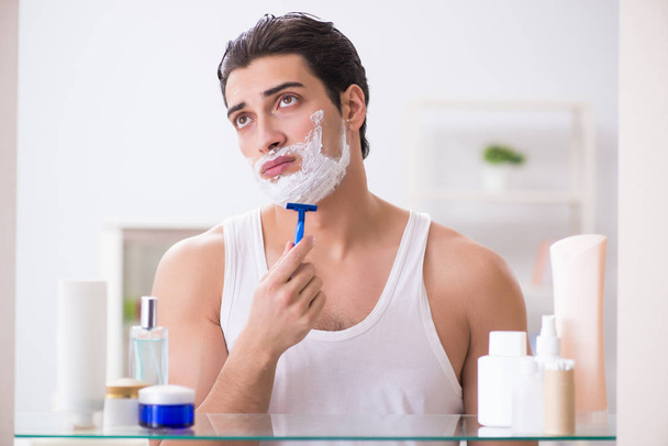 Young handsome man shaving early in the morning at home - Photo, Image