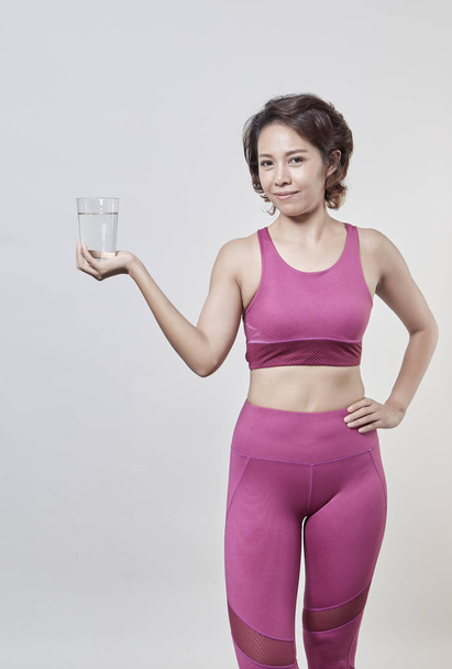 Bir bardak su tutan spor giyim, ağırlık kaybı kavramı Asya kısa saçlı kadın - Fotoğraf, Görsel