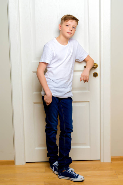 Fashionable little boy near the white door. - Фото, изображение
