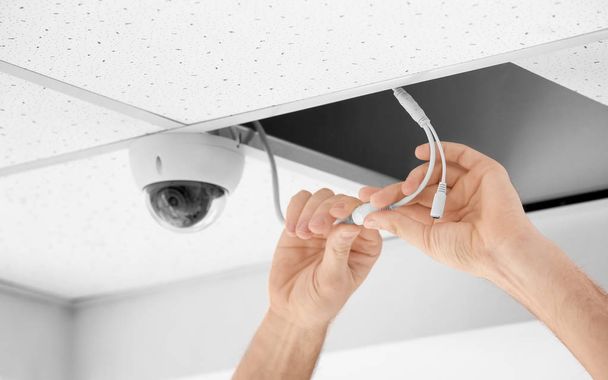 Technician installing CCTV camera on ceiling indoors, closeup - Foto, Imagen