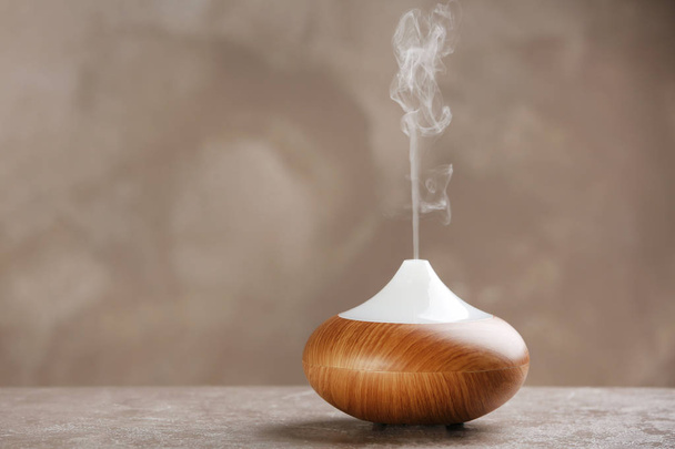 Aroma oil diffuser on table against grey background. Air freshener - Foto, imagen