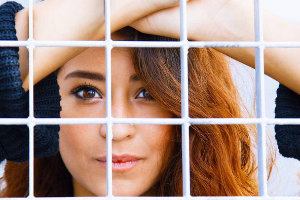 Young woman behind the metal mesh - Photo, image
