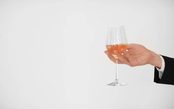 Man holding glass of wine on light background - Zdjęcie, obraz