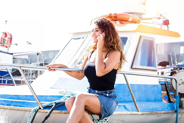 молода брюнетка на палубі яхти говорить на мобільному телефоні
 - Фото, зображення