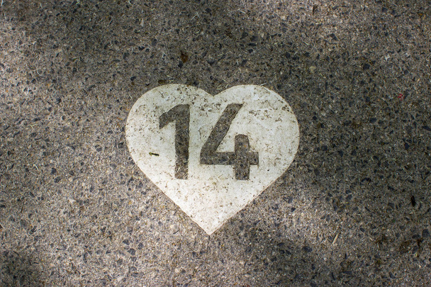 El dígito 14 pintado en el corazón blanco sobre un pavimento
 - Foto, Imagen