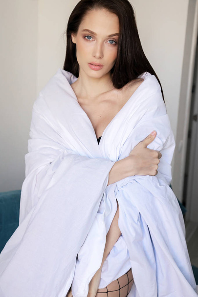 fashion photo of beautiul sexy woman with dark hair in black lingerie posing in bedroom, wrapped in a blanket - Fotó, kép