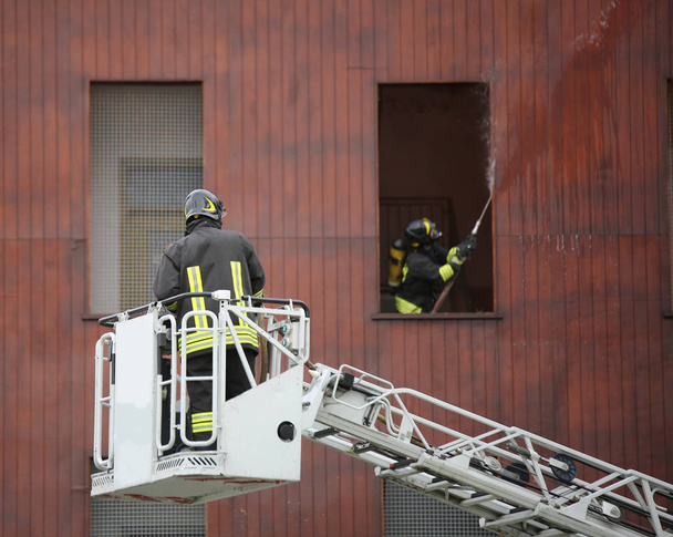 bombeiro em uma escada para chegar aos andares superiores de um edifício e extinguir um incêndio
 - Foto, Imagem
