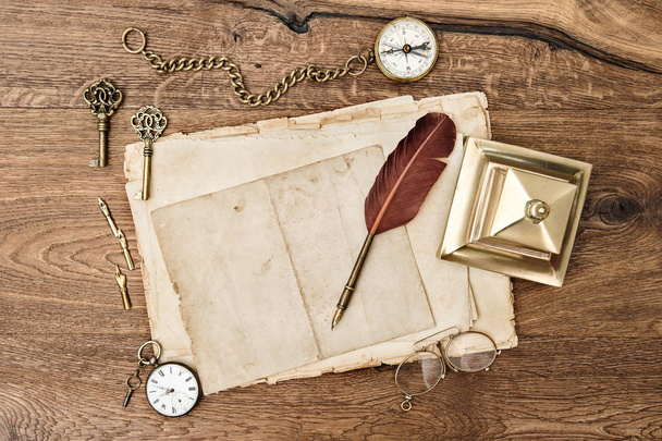 Antique office supplies and accessories on wooden background. Vintage used paper with feather pen - Фото, зображення
