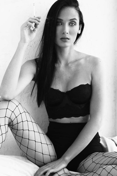 fashion photo of beautiul sexy woman with dark hair in black lingerie posing in bedroom - Фото, зображення