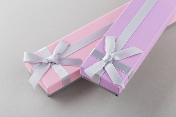 Pink and violet gift boxes with ribbon bows on gray background  - Photo, Image