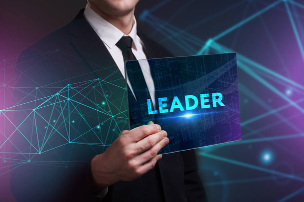Business, Technology, Internet and network concept. Young businessman working on a virtual screen of the future and sees the inscription: Leader - Photo, Image