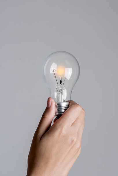 Realistic photo of Light bulb gradully start turn on in woman hand. - Φωτογραφία, εικόνα