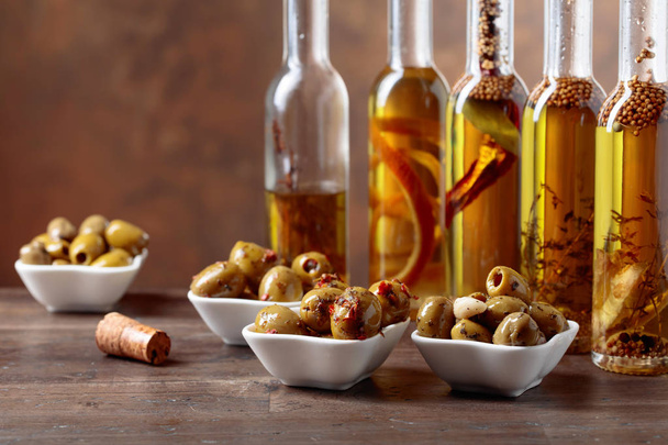 Spiced green olives and bottles with olive oil on a wooden table.  Copy space. - Fotografie, Obrázek