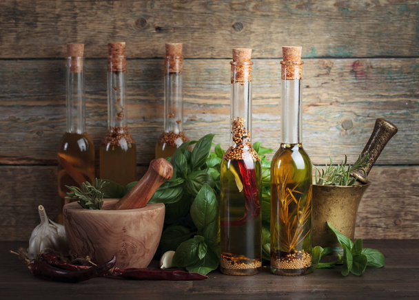 Olive oil with different spices and herbs on a old wooden table. - Foto, imagen
