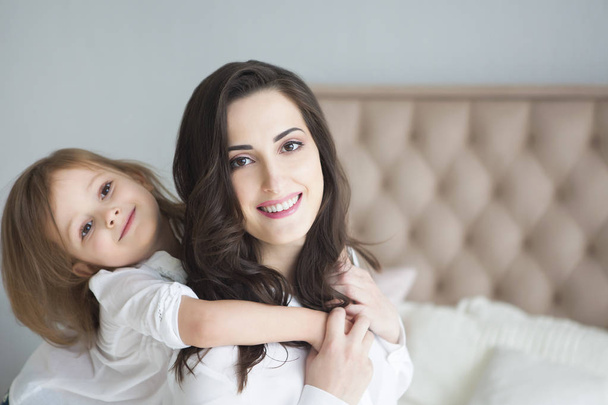 Young woman in the morning embrace with small daughter. Love and family concept - Foto, Bild