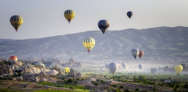 Αερόστατο που πετά πάνω από βραχώδη τοπία στην Καππαδοκία Τουρκίας - Φωτογραφία, εικόνα