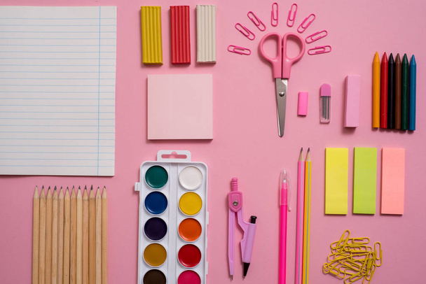 Stationary concept, Flat Lay top view Photo of Scissorsschool supplies, notepad and pens, color pencils, on a pink background. pink background with copy space. - Fotó, kép