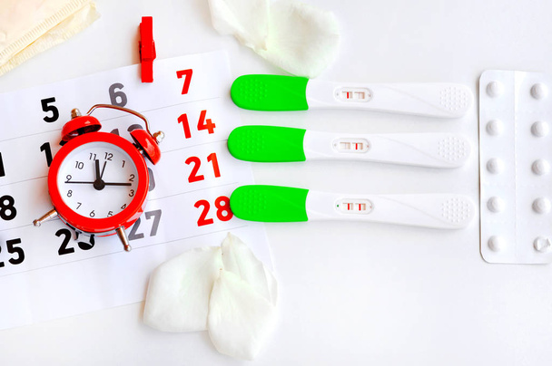 Тестова смуга овуляції з червоним годинником, таблетками контрацепції та менструальними подушечками. Тести показують три різні результати-позитивний результат, це час для дитини. Стерильні дні. Тест не дуже добре зроблено
 - Фото, зображення