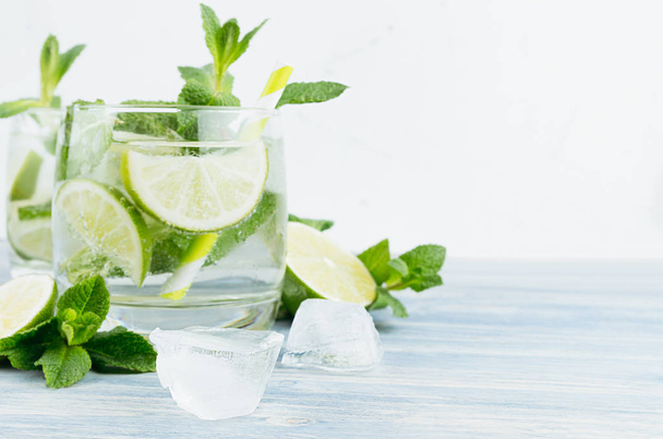 Tropical fresh cold cocktail with mint, lime, ice, straw on light white background, copy space, closeup. - Foto, Imagem
