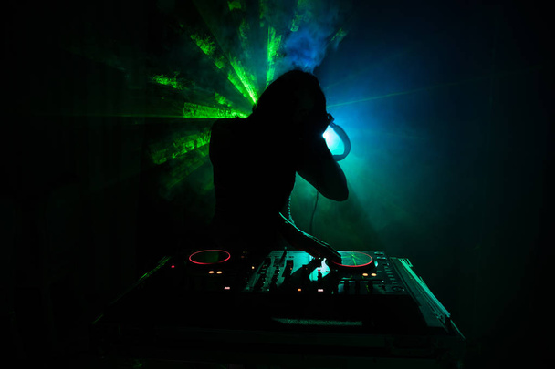 DJ Spinning, Mixing, and Scratching in a Night Club, Hands of dj modifie différents contrôles de piste sur le pont de DJ, feux stroboscopiques et brouillard, ou Dj mélange la piste dans la boîte de nuit à la fête. Concentration sélective
 - Photo, image