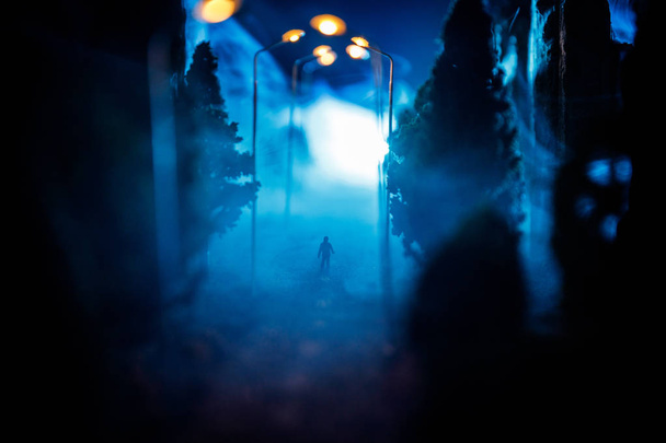 Samotny mężczyzna. Miasta w nocy w gęstej mgle. Gęsty smog na ciemnej ulicy. Sylwetki człowieka na drodze. Dekoracja stołu. Selektywny fokus - Zdjęcie, obraz