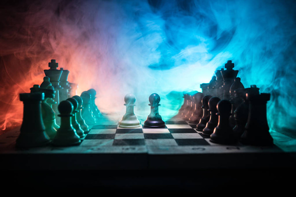 Концепция шахматных настольных игр бизнес-идей, конкуренции и стратегических идей. Шахматные фигуры на темном фоне с дымом и туманом. Концепция делового лидерства и уверенности. Селективный фокус
 - Фото, изображение