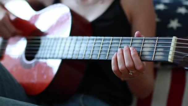 Jonge vrouw met armband op haar hand speelt gitaar en strijkers raakt. - Video