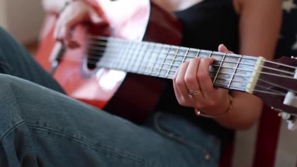 Young woman with bracelet on her hand plays guitar and touches strings. - Felvétel, videó