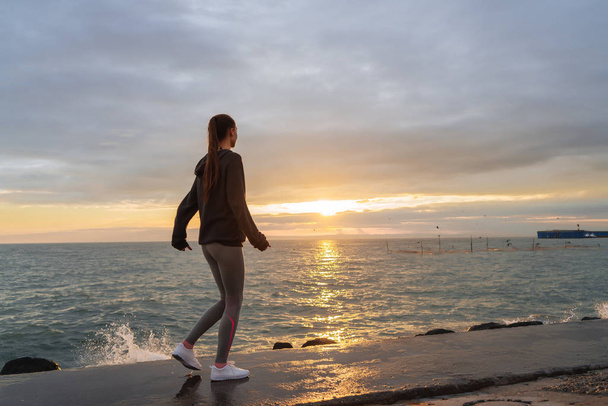 athletic slender girl jogging by the sea at sunset, wants to lose weight - Fotoğraf, Görsel