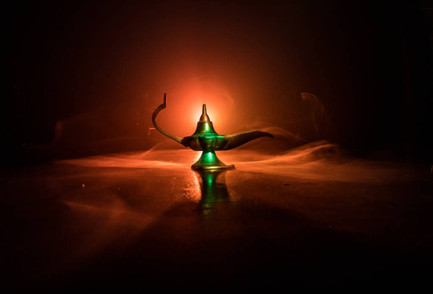 Antique Aladdin arabian nights genie style oil lamp with soft light white smoke, Dark background. Lamp of wishes concept. Selective focus - Photo, Image