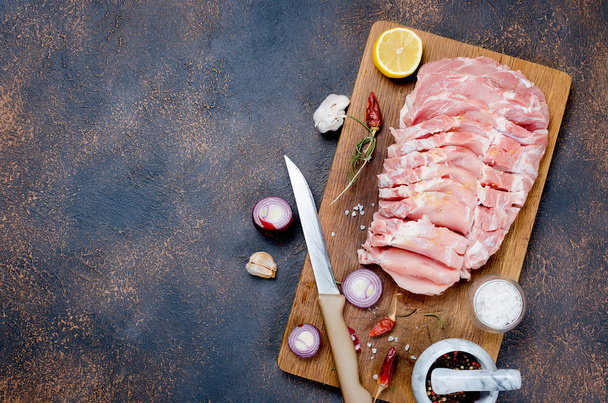 Raw fresh pork meat in marinade with spises and garlic over wooden background,ready for baking. Food background with copy space, top view - Foto, Bild