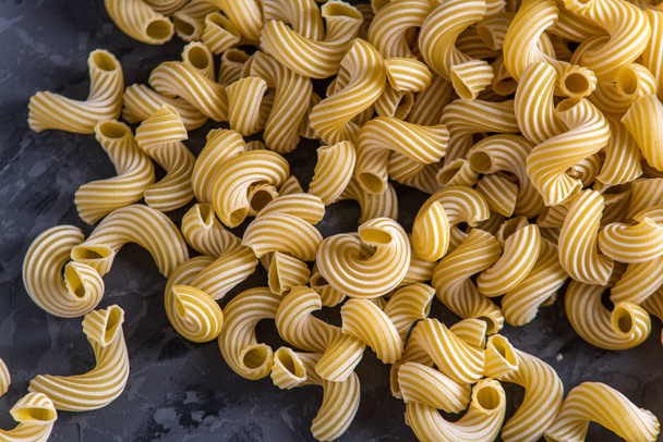 Pâtes italiennes non cuites sous forme de spirales sur un fond sombre. Le concept de composition de la conception des aliments
. - Photo, image