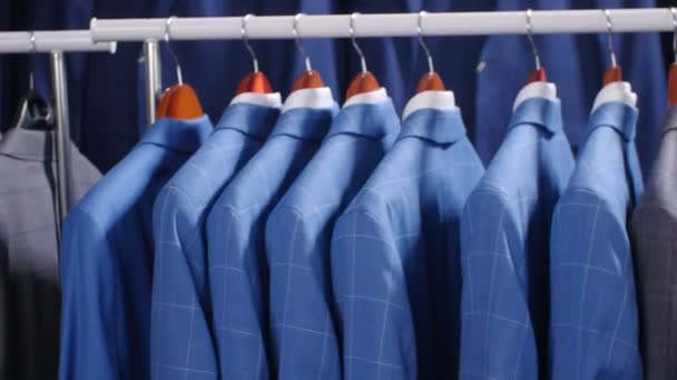 Mężczyźni garnitury i marynarki wiszące w sklepie odzieżowym - Materiał filmowy, wideo