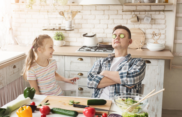 Little girl and dad having fun while cooking in kitchen - Photo, Image