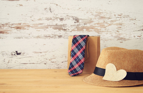 Imagen de sombrero fedora masculino y bolsa de compras con corbata sobre mesa de madera. .. Concepto del día del padre
. - Foto, Imagen