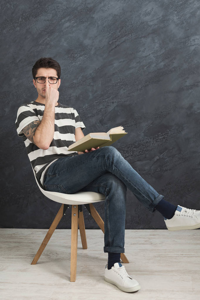 Jeune homme tatoué réfléchi avec un livre
 - Photo, image