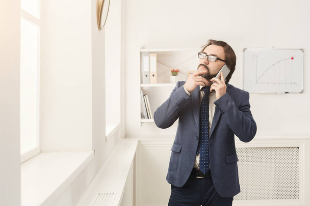 Телефон бізнесмена, що розмовляє по телефону біля вікна
 - Фото, зображення