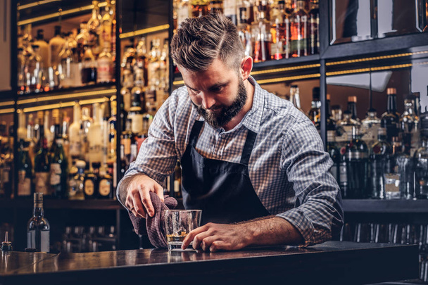 Bir gömlek ve önlük şık acımasız barmen, bir kokteyl bar counter arka plan yapar. - Fotoğraf, Görsel