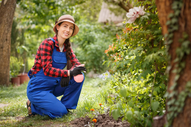 female gardener in work clothes with spray bottle - Foto, afbeelding