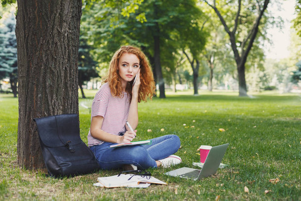 Happy young woman talking on smartphone in park - Photo, Image
