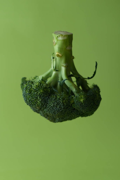Broccoli in the air on a green background - Фото, зображення