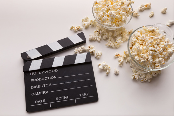 Filmklapper en popcorn op witte achtergrond - Foto, afbeelding