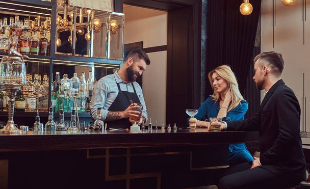 Stylish brutal bartender serves an attractive couple who spend an evening on a date. - 写真・画像
