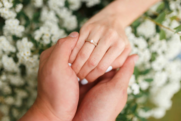 Man giving an engagement ring to his girlfriend In flower garden, holding her hand. Boyfriend Surprised Her Girlfriend With Engagement Ring in flower garden. - Foto, afbeelding