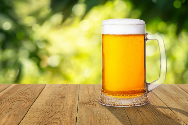 bier met groene onscherpe achtergrond - Foto, afbeelding