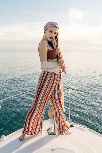 beautiful elegant girl with trendy summer pants posing on her white yacht, long-awaited vacation - Fotó, kép