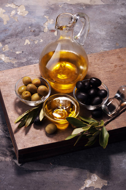 Pullo neitsytoliiviöljyä ja öljyä kulhossa joidenkin oliivien kanssa
. - Valokuva, kuva