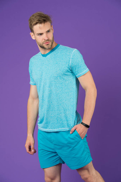 Sportsman in tshirt and shorts on violet background. Man in blue casual clothes. Macho in active wear for workout or training on purple wall. Sport fashion style and trend. Fitness and gym activity. - Foto, Bild
