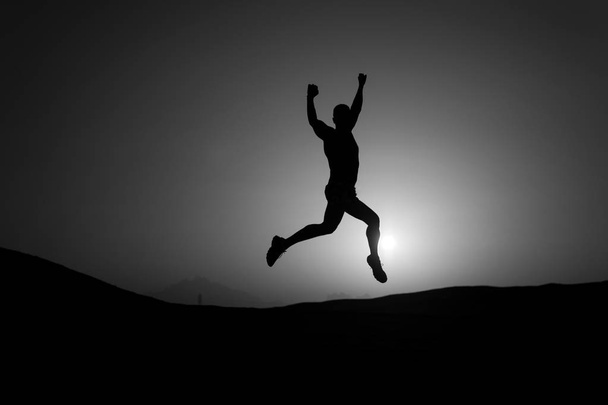 Freedom, energy concept. Athlete with muscular body in dusk. Silhouette of sportsman. Sport, fitness, activity. Man jump on sunset sky background. - Zdjęcie, obraz